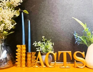 Letters spelling out ACTS and blue tapered candles on the front desk